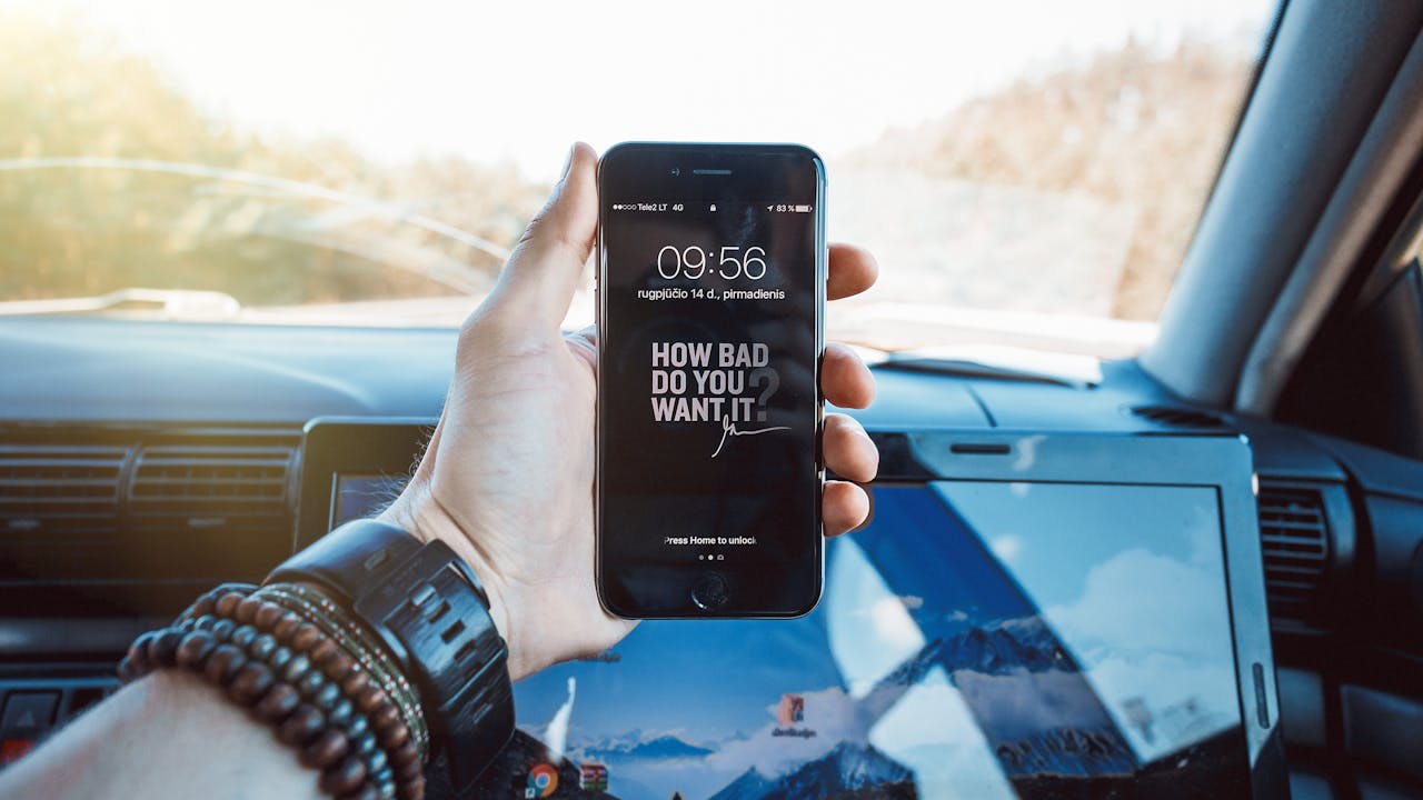 Close-up of a hand holding a smartphone in a car, highlighting technology and motivation.